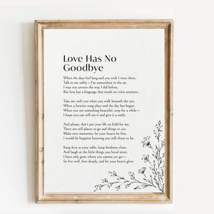 May include: A framed wall art print featuring the poem Love Has No Goodbye in black serif text on a white background. The bottom right corner displays a delicate black line drawing of wildflowers. The frame is made of light brown wood.