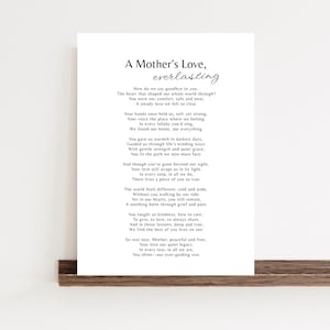 May include: A framed print with the text "A Mother's Love, everlasting" in black script. The poem is printed in a classic serif font. The print is displayed on a dark brown wooden shelf against a white wall.