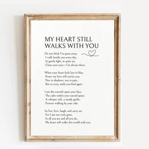 May include: A framed print featuring the poem "MY HEART STILL WALKS WITH YOU" in black text. The poem is set against a white backdrop, with a small heart illustration. The frame is a light brown colour.