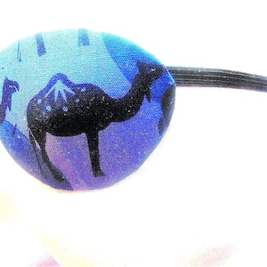 May include: A blue eye patch with a black elastic strap. The patch features a black and white print of camels.
