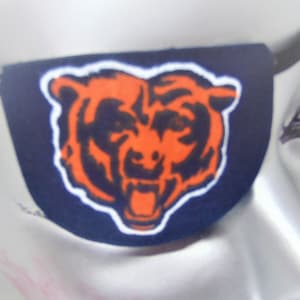 May include: A blue eye patch with an orange and black bear logo. The bear is roaring with its mouth open. The eye patch is made of fabric and has an elastic strap.