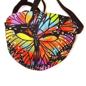 May include: A black sleep mask with an elastic band. The mask is decorated with a colourful butterfly pattern.