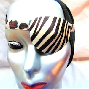May include: A black and white zebra print eye patch with a leopard print headband. The eye patch is worn on a mannequin head.