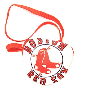 May include: Red and white eye patch with an elastic strap. The patch features the Boston Red Sox logo with the words "Boston Red Sox" and a baseball with two red socks.