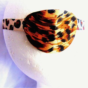 May include: A brown and black leopard print eye patch with an elastic band.