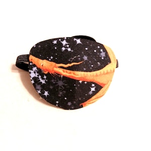 May include: A black eye patch with a white and orange dragon design on a black background with white stars.