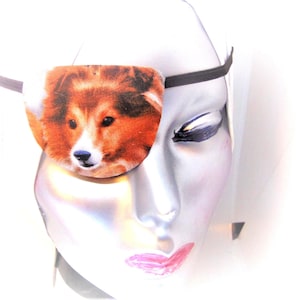 May include: A white mannequin head with a black eye patch featuring a brown and white dog. The eye patch is made of fabric and has a printed image of a dog.