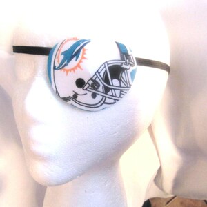 May include: A white eye patch with a blue and orange Miami Dolphins logo and a black helmet graphic.