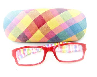 Könnte beinhalten: Ein rotes Brillenetui mit einem bunten Karomuster und eine rote Brille mit einem regenbogenfarbenen Streifenmuster auf der Innenseite.