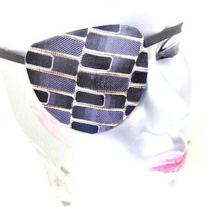 May include: A black and gold patterned eye patch with an elastic strap.