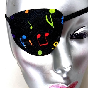 May include: A black eye patch with a colorful musical note pattern. The eye patch has an elastic strap.