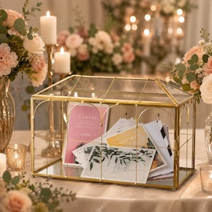 May include: A rectangular glass card box with a gold metal frame and a hinged lid. The box contains several cards with the word LEAVES printed on them, featuring botanical illustrations and pink, yellow, and white color schemes.