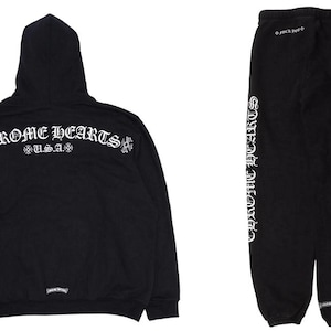 May include: Black hoodie and sweatpants set. The hoodie features the text "CHROME HEARTS U.S.A." in white script across the back. The sweatpants have "CHROME HEARTS" printed vertically down the side in white script. A Titan Hub logo is visible.