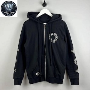 May include: Black zip-up hoodie with white graphic designs on the sleeves, chest, and back. The hoodie features a hood, pockets, and a zip closure. The brand logo is visible on the chest.