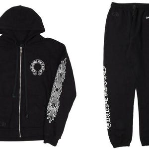 Puede incluir: Conjunto negro de sudadera con cremallera y pantalón de chándal a juego. La sudadera con capucha presenta diseños decorativos blancos en las mangas y un logotipo. El pantalón de chándal tiene texto blanco en el lateral.