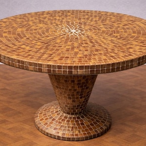 May include: Round mosaic table with a pedestal base. The tabletop and base are covered in small, square tiles in shades of brown and tan, creating a textured surface. The table is a decorative furniture piece.