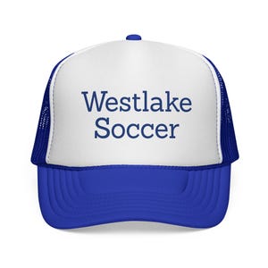 May include: A blue and white trucker hat featuring the text "Westlake Soccer" in blue. The hat has a blue peak and a white front panel with the text. The sides and back of the hat are blue mesh.