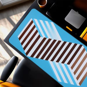 May include: A rectangular desk mat featuring a bright blue background with a large, central geometric pattern composed of alternating diagonal brown and white stripes that form a chevron-like shape across the surface of the mat.