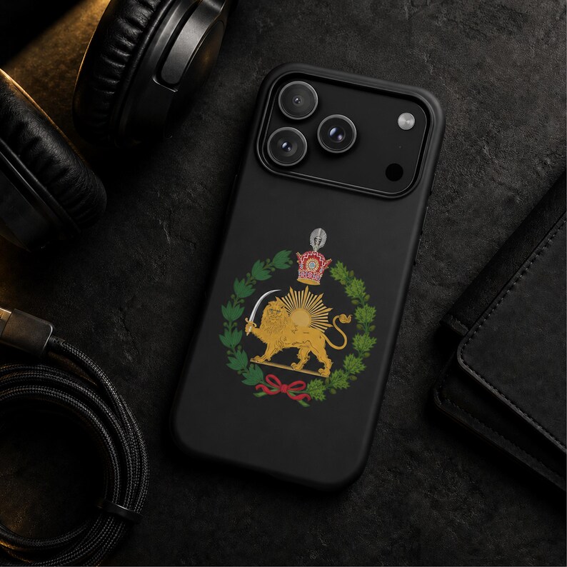 Puede incluir: Una funda de smartphone en negro mate con un emblema central del Le&oacute;n y el Sol. El dise&ntilde;o muestra un le&oacute;n dorado sosteniendo una espada frente a un sol naciente, rodeado por una corona de laurel verde y rematado con una corona real.