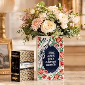 May include: A rectangular ceramic vase featuring a peacock illustration, red floral patterns, and the text "I declare after all there is no enjoyment like reading!" alongside a book-shaped container titled "The Great Gatsby" with gold accents.