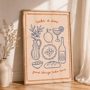 Könnte beinhalten: Ein gerahmter rechteckiger Wandkunstdruck mit hellpfirsichfarbenem Hintergrund und einer dunkelblauen Strichzeichnung, die eine Vase mit Zweigen, eine Zitrone, ein Cocktailglas, einen Kuchen, eine Flasche, eine Schale mit Oliven und Brot zeigt. Text take it slow.