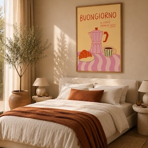 Può includere: Una stampa artistica rettangolare da parete con sfondo giallo chiaro e il testo BUONGIORNO IL CAFFÈ PRIMA DI TUTTO in rosso. L'illustrazione raffigura una moka rosa, una tazza da caffè a righe e un cornetto su una tovaglia rosa a onde.