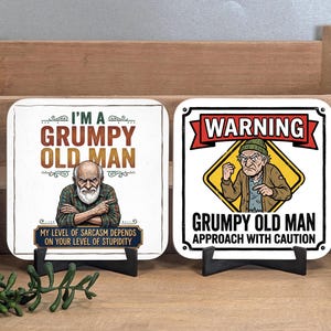 May include: Two square coasters featuring illustrations of an older person. The left coaster reads I'M A GRUMPY OLD MAN MY LEVEL OF SARACASM DEPENDS ON YOUR LEVEL OF STUPIDITY. The right coaster reads WARNING GRUMPY OLD MAN APPROACH WITH CAUTION.