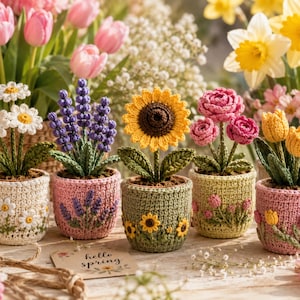 May include: A collection of five crocheted potted plants featuring a daisy, lavender, sunflower, pink roses, and yellow tulips. Each plant is housed in a matching crocheted pot decorated with floral motifs. A small card reads hello spring.