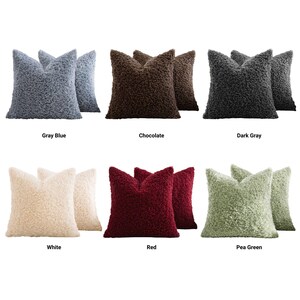 May include: A collection of six sets of square throw pillows featuring a textured, curly faux-shearling fabric. The colors include gray blue, chocolate brown, dark gray, white, red, and pea green, each labeled with its respective color name.