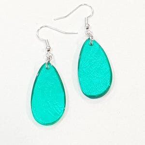 Op de afbeelding: Een paar turquoise teardrop oorbellen met zilverkleurige oorhaken. De oorbellen hebben een getextureerd oppervlak en een glanzende afwerking. Een eenvoudig maar elegant accessoire.