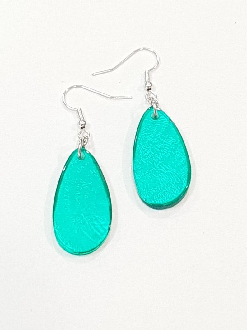 Op de afbeelding: Een paar turquoise teardrop oorbellen met zilverkleurige oorhaken. De oorbellen hebben een getextureerd oppervlak en een glanzende afwerking. Een eenvoudig maar elegant accessoire.