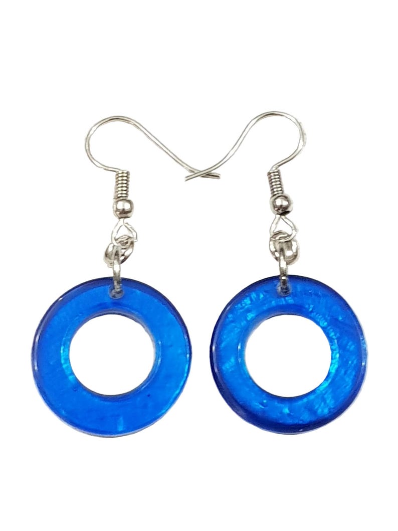 K&ouml;nnte beinhalten: Ein Paar blaue Creolen. Jeder Ohrring hat einen durchscheinenden, kreisf&ouml;rmigen blauen Anh&auml;nger mit einem silberfarbenen Haken. Die Ohrringe sind zum Tragen bestimmt und verleihen jedem Outfit einen Farbtupfer.