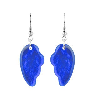 May include: A pair of blue heart-shaped earrings. Each earring has a silver-colored hook and a translucent, textured blue heart pendant. The earrings are displayed against a white background.