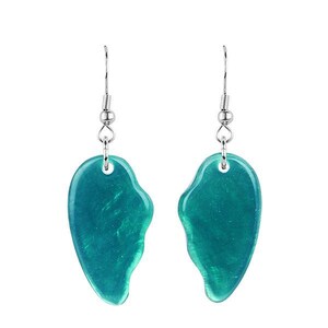 May include: A pair of teal-colored earrings with a heart-shaped design. The earrings have a silver-colored hook and are made of a translucent material. The earrings are displayed against a white background.