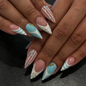 Può includere: Unghie a stiletto con un mix di design che includono smalto azzurro, strisce bianche e punte alla francese. La manicure è decorata con piccoli puntini azzurri in rilievo e minuscole perline metalliche dorate sulla superficie dell'unghia.