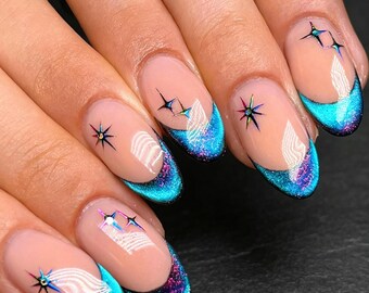 Uñas postizas minimalistas con diseño de galaxia, con purpurina Aurora personalizada, punta iridiscente azul y morada degradada y calcomanías de estrellas multicolor.