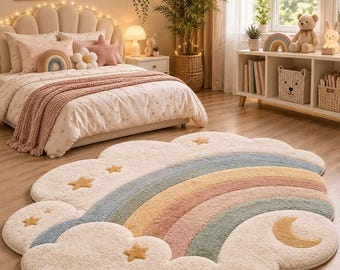 May include: A plush, cloud-shaped area rug featuring a textured rainbow design in soft pastel tones of blue, yellow, and pink. The rug is decorated with several small, yellow tufted stars and a crescent moon, all set against a cream-colored background.