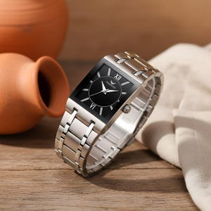 Könnte beinhalten: Eine rechteckige Edelstahl-Uhr mit schwarzem Zifferblatt und silbernen Zeigern. Die Uhr hat ein silbernes Armband und der Text "FNGEEN" ist auf dem Zifferblatt sichtbar. Die Uhr wird auf einer Holzoberfläche präsentiert.