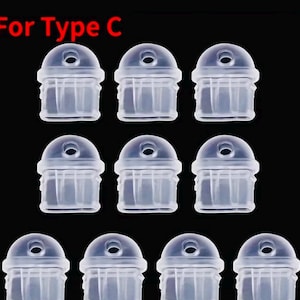 May include: A collection of clear, plastic Type C caps, arranged in three rows against a black background. Each cap has a rounded top with a small hole and a ridged, cylindrical body. The text "For Type C" is visible in the upper left corner.