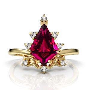 May include: A gold ring featuring a large, kite-shaped, deep pink gemstone as the centrepiece. The setting is adorned with several small, round, clear white accent stones arranged in a symmetrical pattern around the central kite-shaped gem.