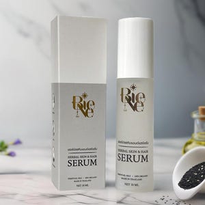 May include: A white and gray box and bottle of Rie Ne Herbal Skin & Hair Serum. The bottle has a white cap and a clear body with the product name and details in black. The box has the same design and text. The product contains essential oils and is 100% organic.