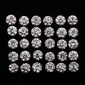 Peut inclure: Une collection de diamants ronds taille brillant, disposés en grille sur fond noir. Chaque diamant présente de multiples facettes, reflétant la lumière. L'image met en valeur la clarté et l'éclat des pierres précieuses.