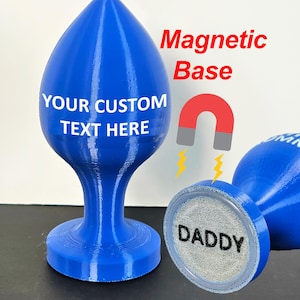 May include: Blue, teardrop-shaped object with a magnetic base. The text "YOUR CUSTOM TEXT HERE" is printed on the front. The text "Magnetic Base" is printed in red. The base of the object has the word "DADDY" printed on it.