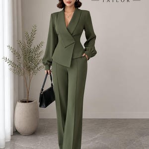 May include: An olive green two-piece suit featuring a blazer with a deep V-neckline, long sleeves with gathered cuffs, and a wrap-style front closure. The matching trousers are high-waisted with a straight-leg cut. The text ZAYRO TAILOR is visible.