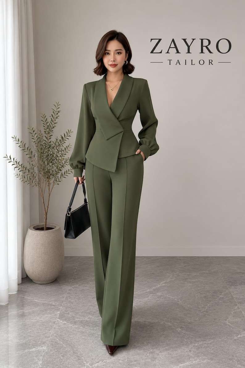 May include: An olive green two-piece suit featuring a blazer with a deep V-neckline, long sleeves with gathered cuffs, and a wrap-style front closure. The matching trousers are high-waisted with a straight-leg cut. The text ZAYRO TAILOR is visible.
