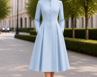 May include: A light blue coat with a high mandarin collar, long sleeves, and a button-down front. The garment features a fitted bodice that transitions into a pleated, flared skirt reaching below the knees. The text ZAYRO TAILOR is visible.
