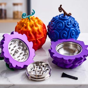 May include: A collection of novelty grinders in the shape of colorful, textured fruits. The grinders are in shades of orange, red, blue, and purple, with a silver grinding mechanism. A small black scraper is also included.