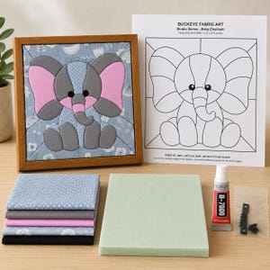 May include: A craft kit featuring a framed fabric art piece of a baby elephant, a printed pattern sheet labeled Buckeye Fabric Art, a stack of five folded fabric squares, a rectangular foam board, a tube of B-7000 glue, and a small metal hanger.