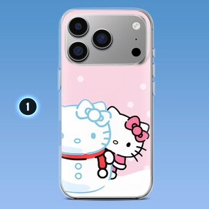 Puede incluir: Una funda transparente para smartphone con un gr&aacute;fico impreso de un personaje de gato blanco con un lazo rosa junto a un mu&ntilde;eco de nieve. El fondo es rosa claro con c&iacute;rculos blancos y tiene un recorte para un sistema de triple c&aacute;mara.
