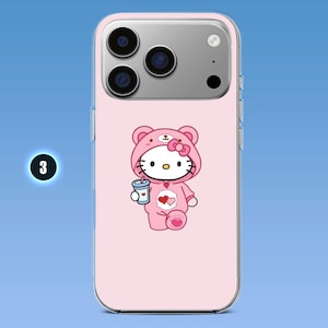 Puede incluir: Una funda de smartphone rosa claro con un gr&aacute;fico de un personaje de gato blanco que lleva una capucha de oso rosa y sostiene una bebida azul. El personaje tiene un lazo rosa, bigotes negros y un emblema de coraz&oacute;n en el pecho. El n&uacute;mero 3 es visible.